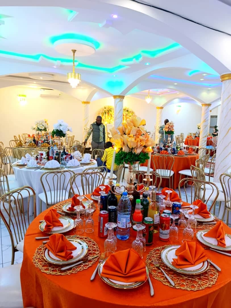 Tables rondes dressées en orange et or avec colonnes marbrées dans la Salle Haut de Gamme